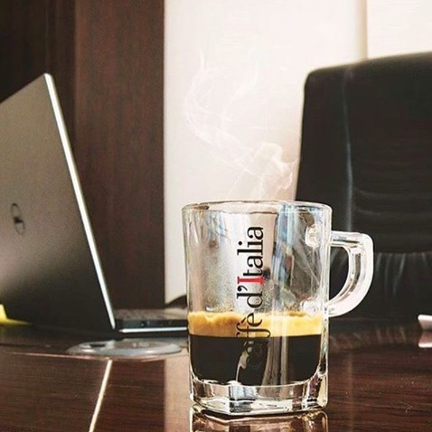 Koffie van Caffè d'Italia in een glas op een bureau met laptop