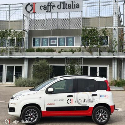 Een auto van Caffè d'Italia vlak voor een fabriek in Toscane