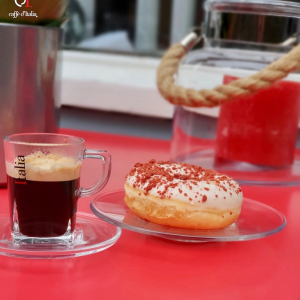 Italiaanse koffie in glas met een donut op een rode tafel