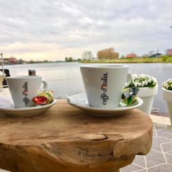 Terras met koffiekopjes en een prachtig uitzicht over het water